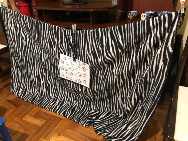 Cortina de teatro improvisada, com um cobertor, na sala de casa.