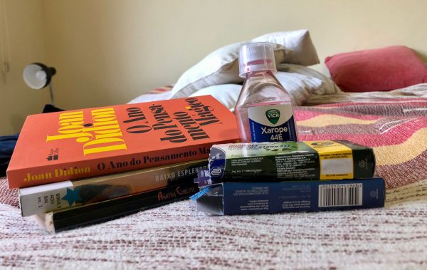 Livros e remédios em cima da cama.