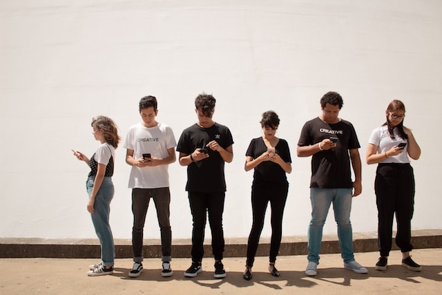 Foto mostra vários adolescentes lado a lado, todos eles olhando para a tela do celular e sem interagir entre si.