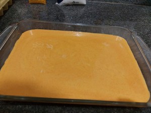 Massa do bolo de cenoura em tabuleiro untado com manteiga, pronta pra assar.