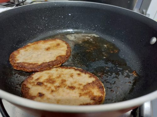 Hambúrguer fritando na frigideira.