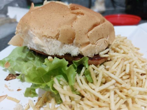 Hambúrguer pronto, com batata-palha ao redor.