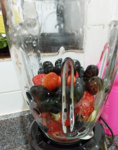 Suco de frutas vermelhas, com morangos e uvas roxas.