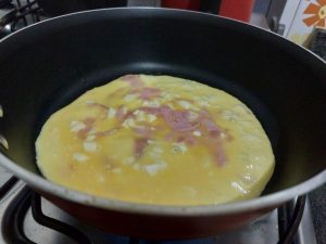 Preparo da omelete de presunto na frigideira.