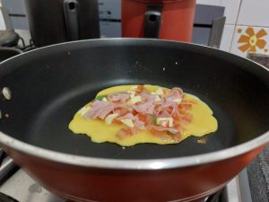 Preparo da omelete com tomate na frigideira.