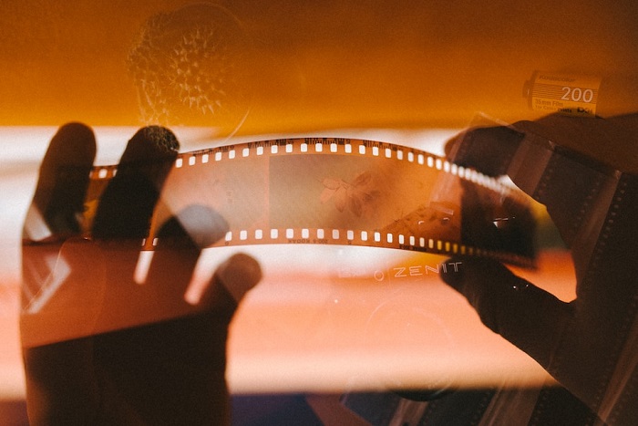Filme negativo de fotografia analógica, segurado por duas mãos, em tom de sépia, remetendo ao passado, a lembranças antigas, memórias.