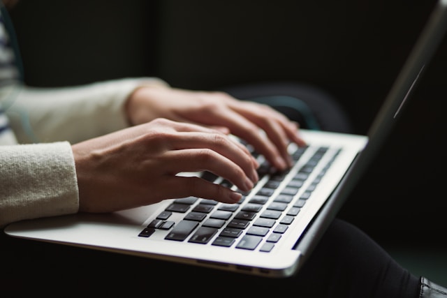 Escritora, mulher escrevendo texto em computador. Foto: Kaitlyn Baker / Unsplash