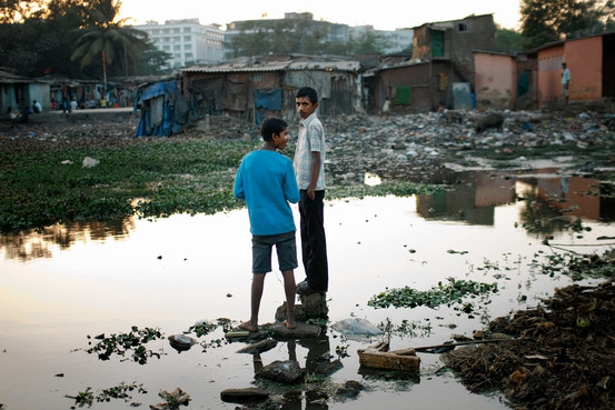 Imagem do lago de esgoto de Annawadi, favela em Mumbai, na Índia, retratada no livro de Katherine Boo. Na foto de Chiara Goia, dois amigos do personagem Sunil.