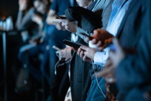 Pessoas usando o telefone em pé. Imagem ligada a estes conceitos: negócio povo Redes Sociais cinza Smartphone mídia social importante conectado telefone inteligente